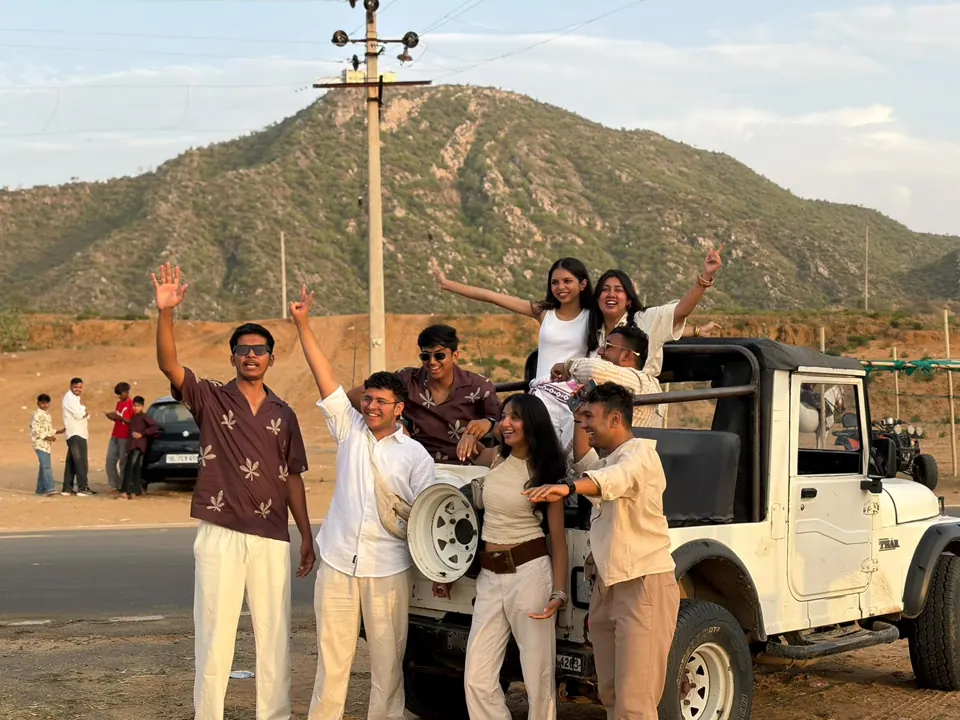 Safari guests beside a white jeep with the hills of Pushkar behind them