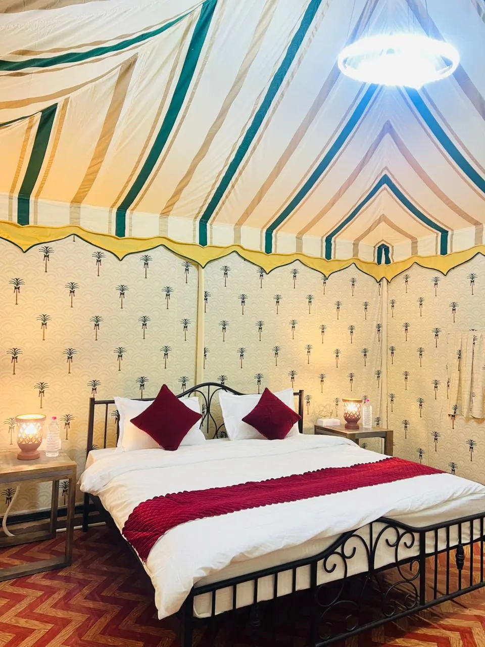 Patterned Swiss tent interior with a furnished bed and bedside lighting