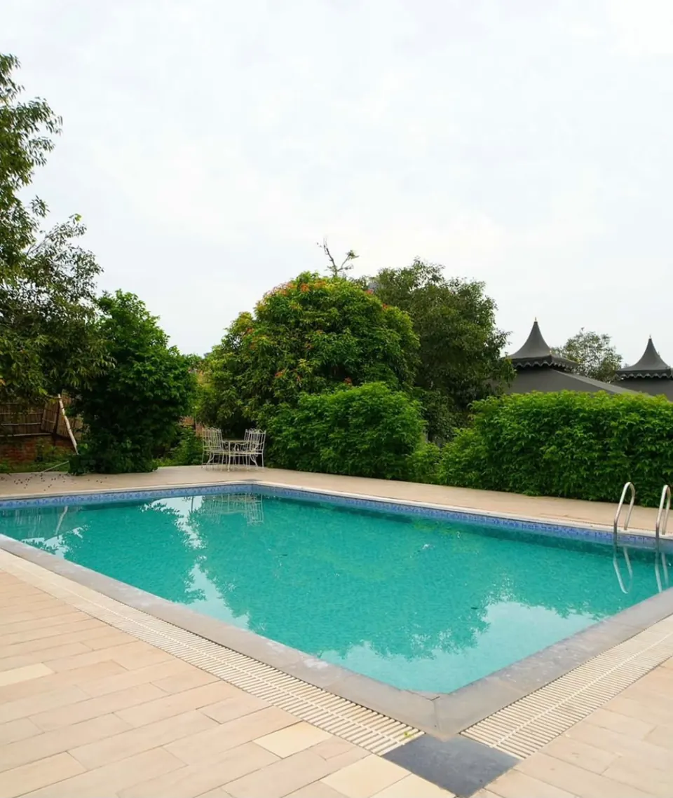 Camp swimming pool bordered by a paved terrace and green trees